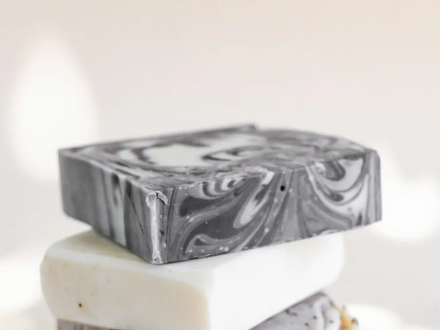 A black charcoal-swirled bar balanced on top of a plain white one