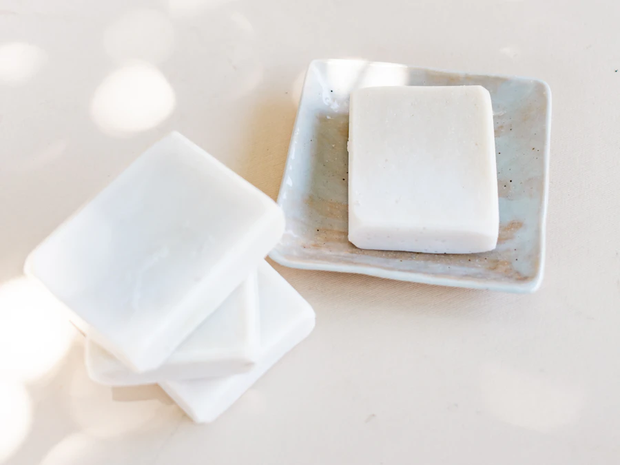 Pale olive-oil bars beside a small glazed ceramic soap dish