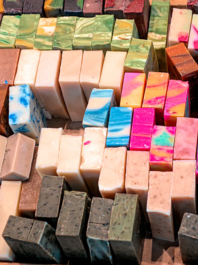 A market table stacked with brightly coloured soap blocks