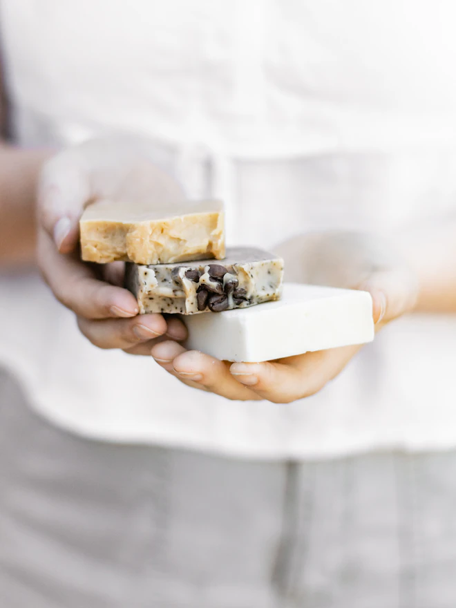 A person in a linen shirt holding two bars of soap